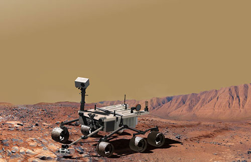 This images shows a hilly, layered martian landscape, with the car-sized Mars Science Laboratory rover reaching out with its robotic arm to study rocks.  The rover's mast, or 'neck,' is off-center, rising from the right-hand corner of the rover's square 'body.'  Its rectangular head-like box has a camera that resembles a single eye, gazing down on the bedrock below.  Large rover tracks extend far into the distance.