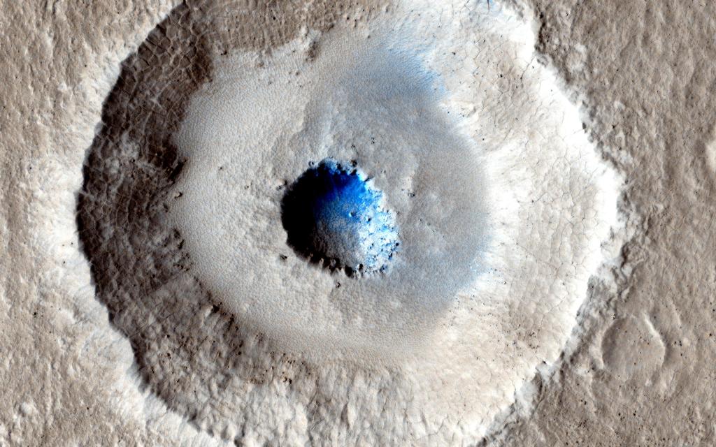This is an image of a small, gray impact crater with a bowl-shaped rim.