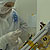 In this image, a Caucasian man wears a white, protective suit in a cleanroom.  His face is mostly covered and his hands are gloved.  He is working on the CRISM instrument for the Mars Reconnaissance Orbiter mission.  The instrument sits on a slanted aluminum-like board covered with yellow Kapton tape - a low-static tape safe for using in cleanrooms and near or on instrumentation.