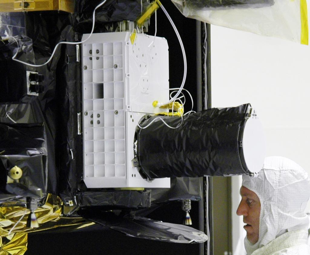 With the Compact Reconnaissance Imaging Spectrometer for Mars (CRISM) instrument just above his head, a technician at NASA's Kennedy Space Center works on the Mars Reconnaissance Orbiter spacecraft in July 2005.