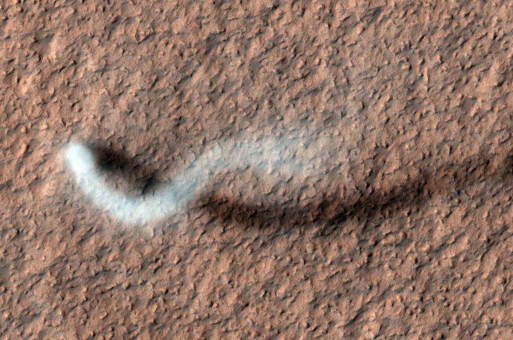 A towering dust devil, casts a serpentine shadow over the Martian surface in this image acquired by the High Resolution Imaging Science Experiment (HiRISE) camera on NASA's Mars Reconnaissance Orbiter.